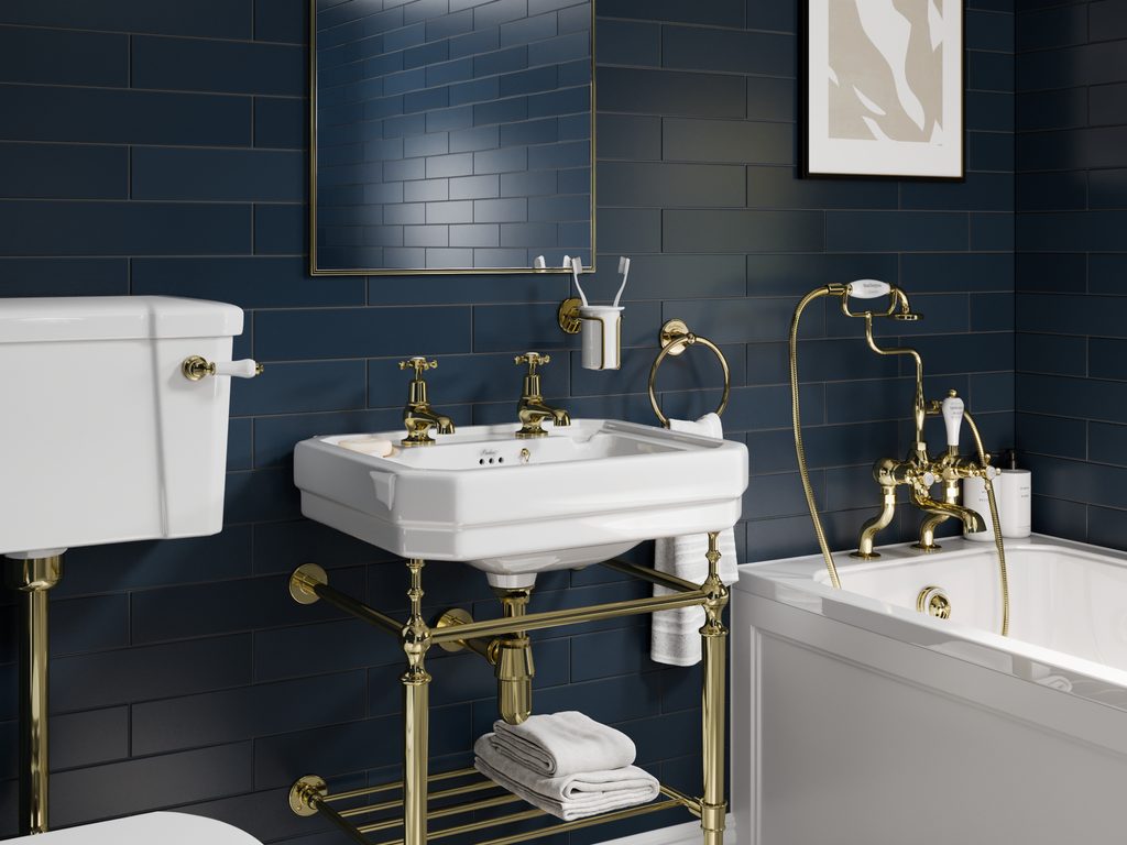 Burlington Cameo Collection traditional luxury bathroom — navy metro tile wall, polished brass console basin with twin pillar taps, gold-trim mirror, brass framed bath shower mixer — tile and brassware coordinated as a single specification