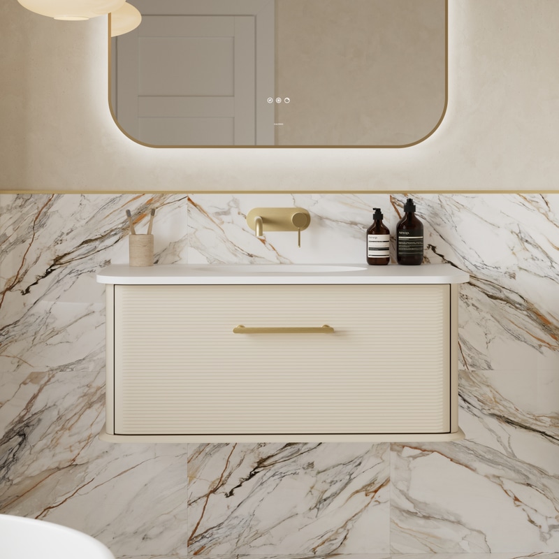 Calypso wall-mounted brass tap set into marble tile above a wall-hung vanity basin