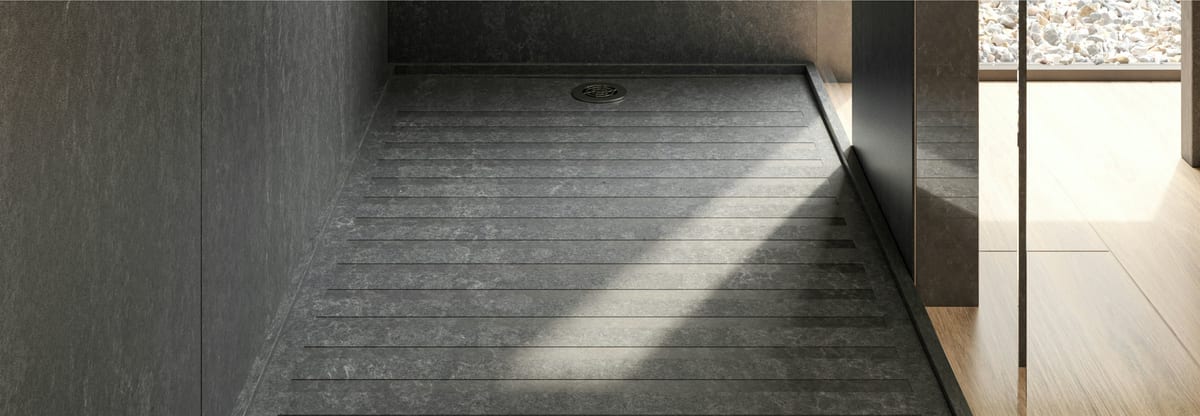 Cosentino Earthic shower tray in a dark stone finish, with a grooved textured floor falling to a central drain