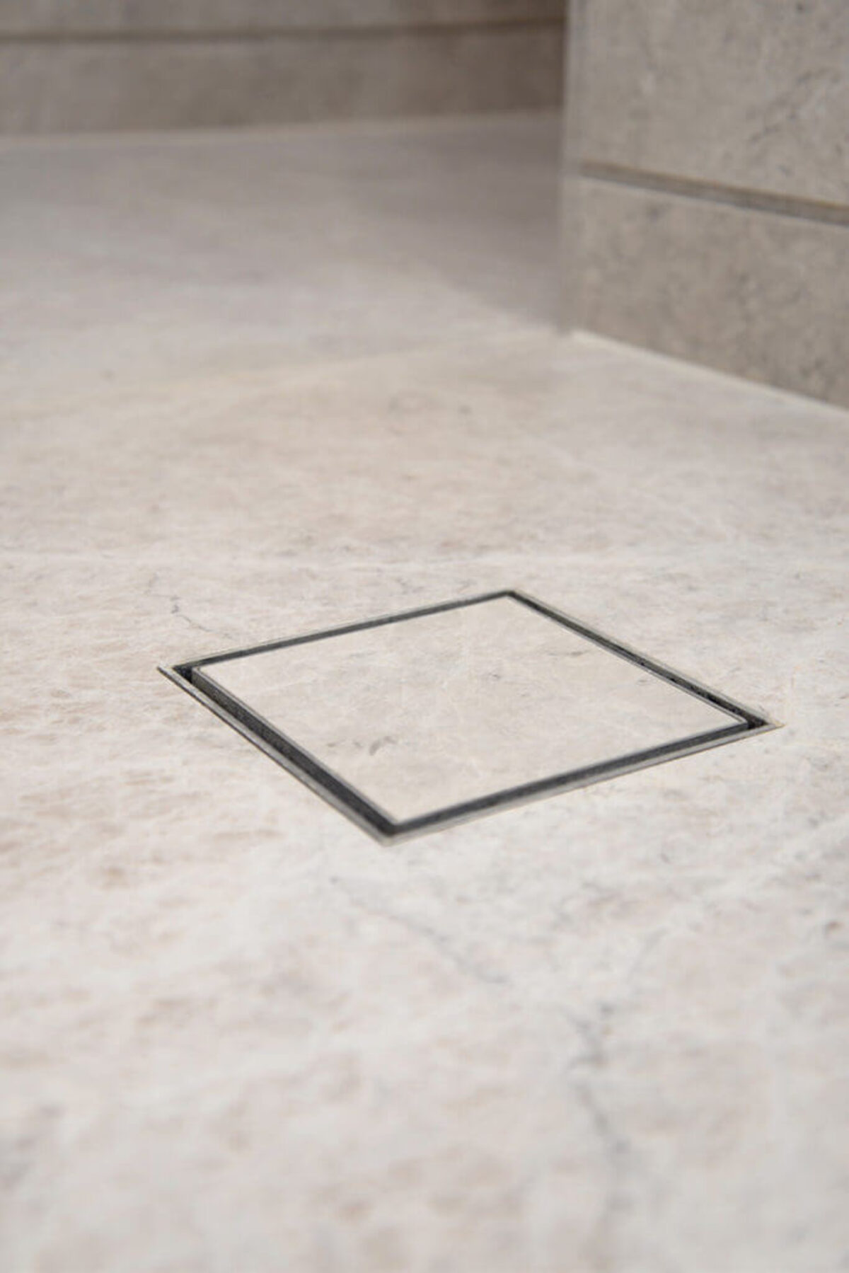 Flush trayless wet-room drain set into stone-effect tile, no step or tray lip