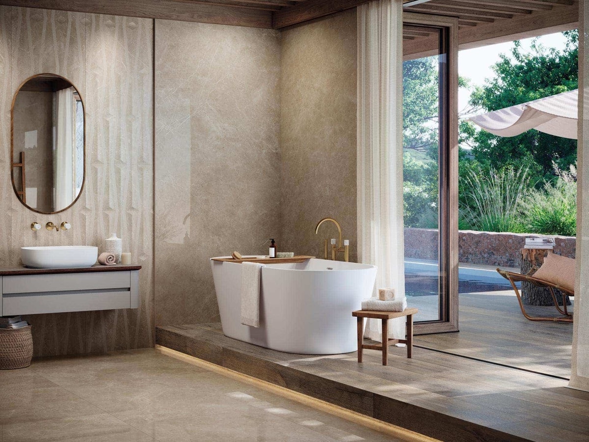 Porcelanosa large-format stone-effect porcelain lining a bathroom with a freestanding tub and a garden terrace beyond