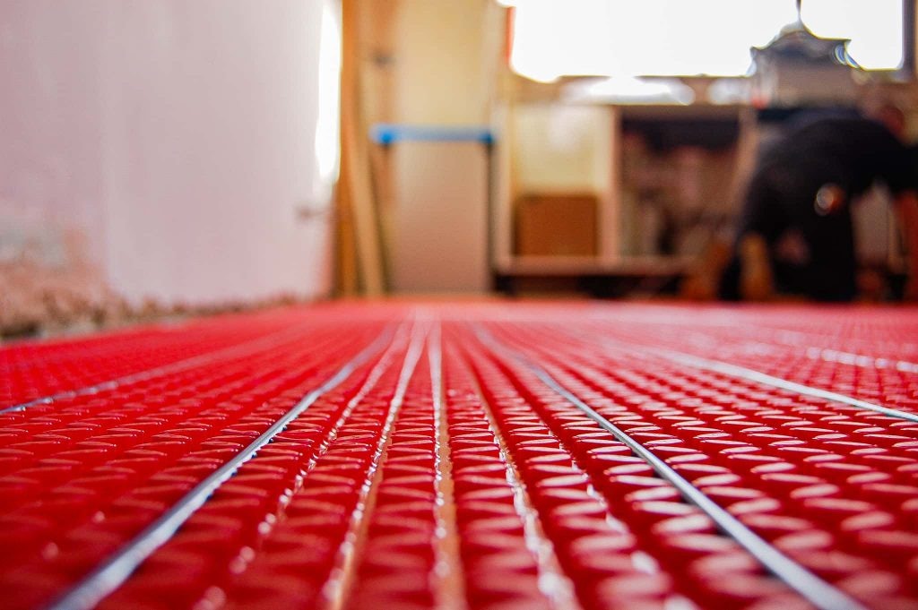 Warmup electric underfloor heating loose wire installed across a prepared bathroom subfloor before tile adhesive and porcelain tiles - the thin resistance element that adds only 5-15mm to floor build-up in a UK bathroom retrofit