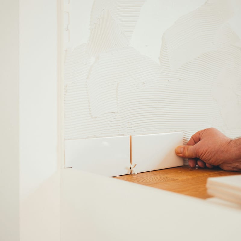 Close-up of tile being installed by hand during a bathroom renovation