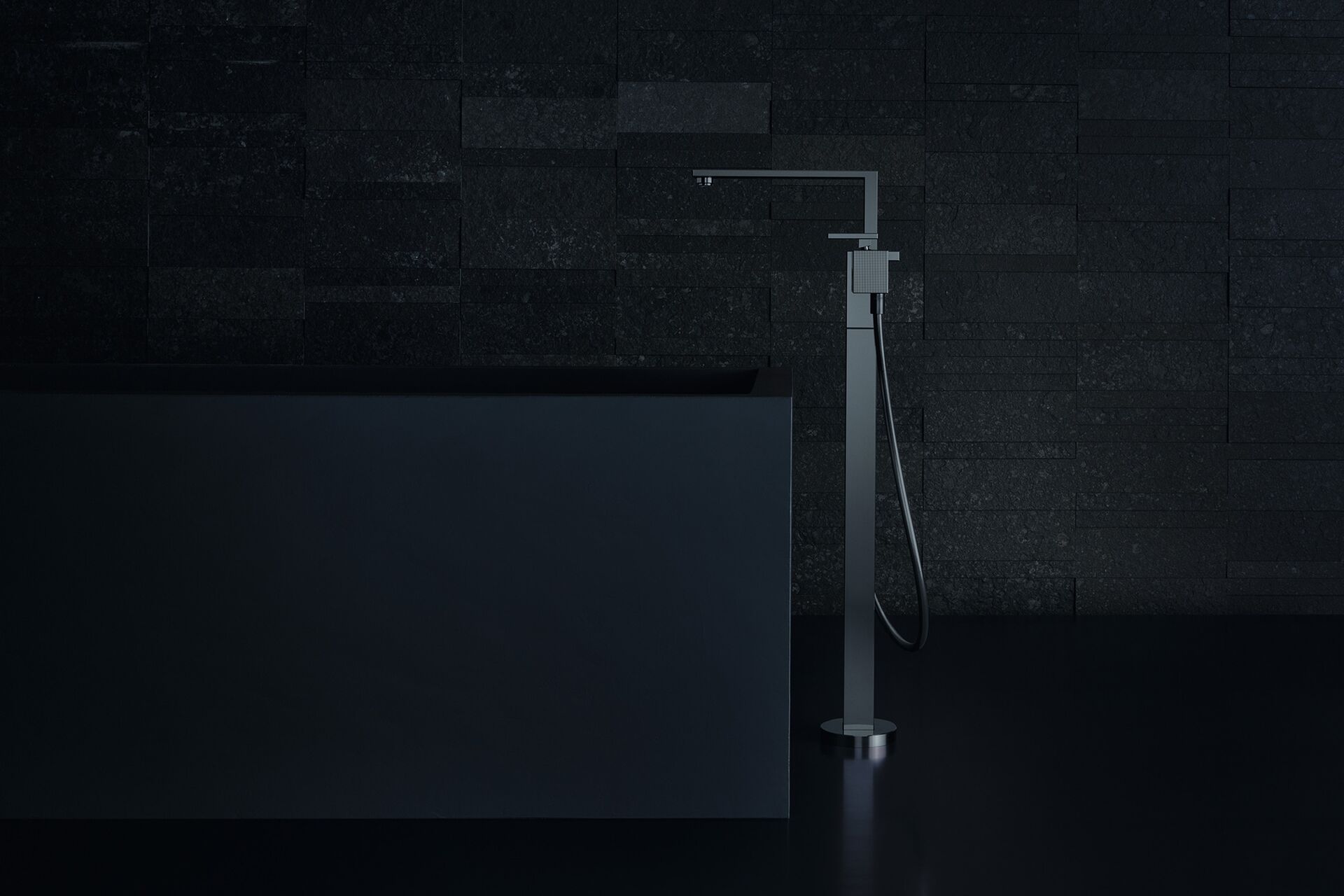 AXOR Edge floorstanding bath mixer in Polished Black Chrome beside a dark bath.