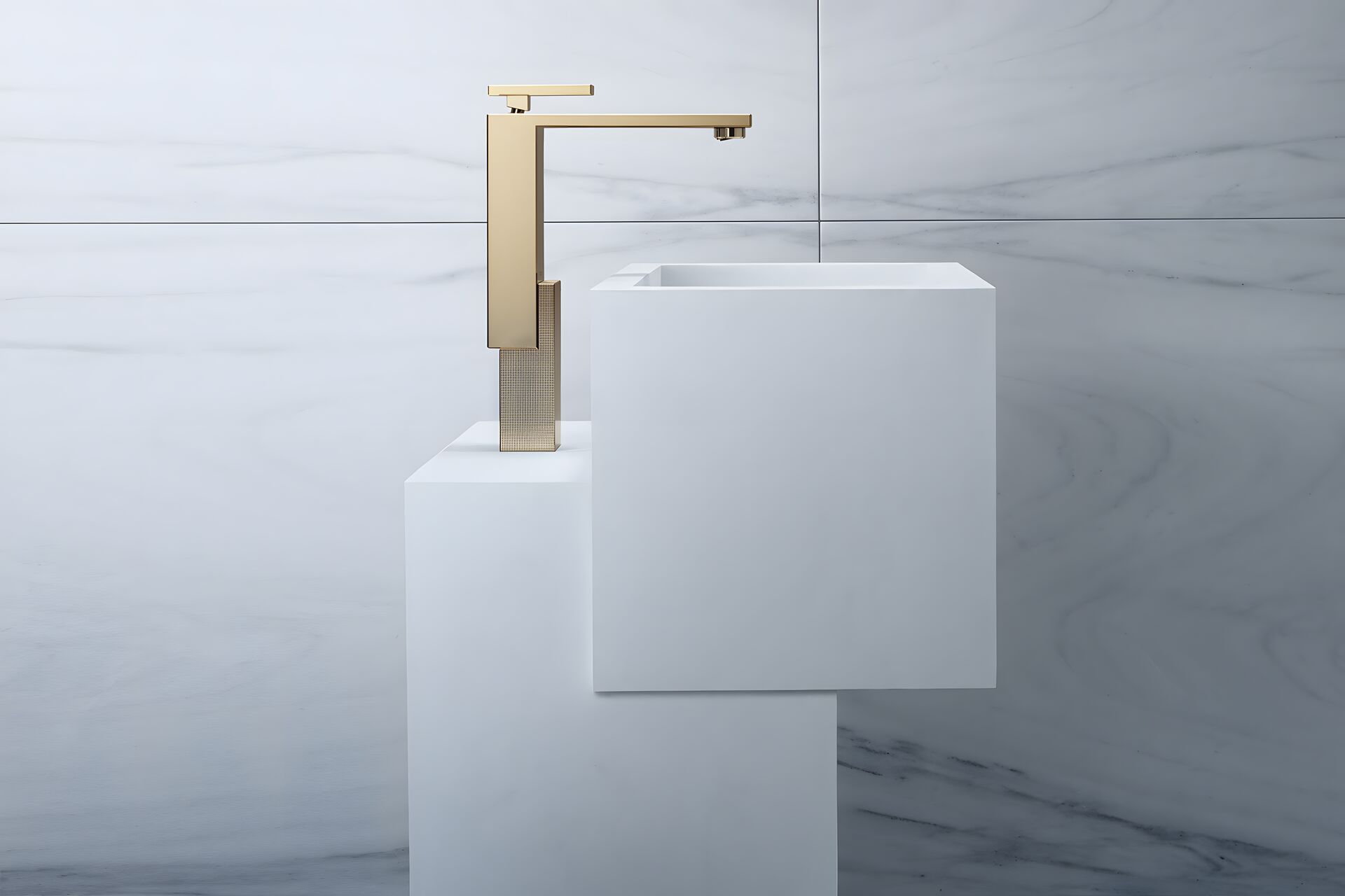 AXOR Edge basin mixer in Polished Gold Optic beside a white rectangular basin.