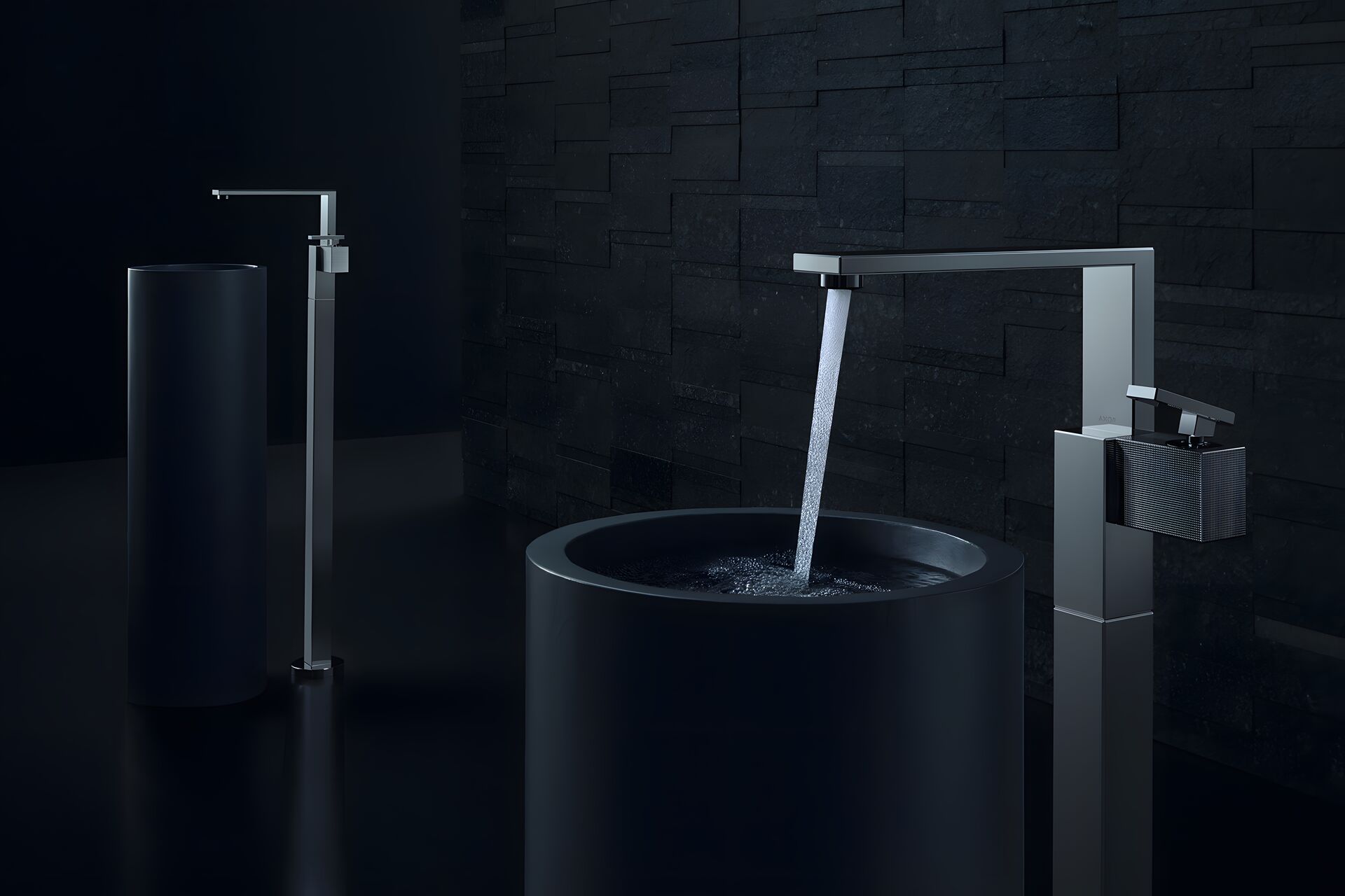 AXOR Edge basin mixers with a visible water jet above a dark round basin