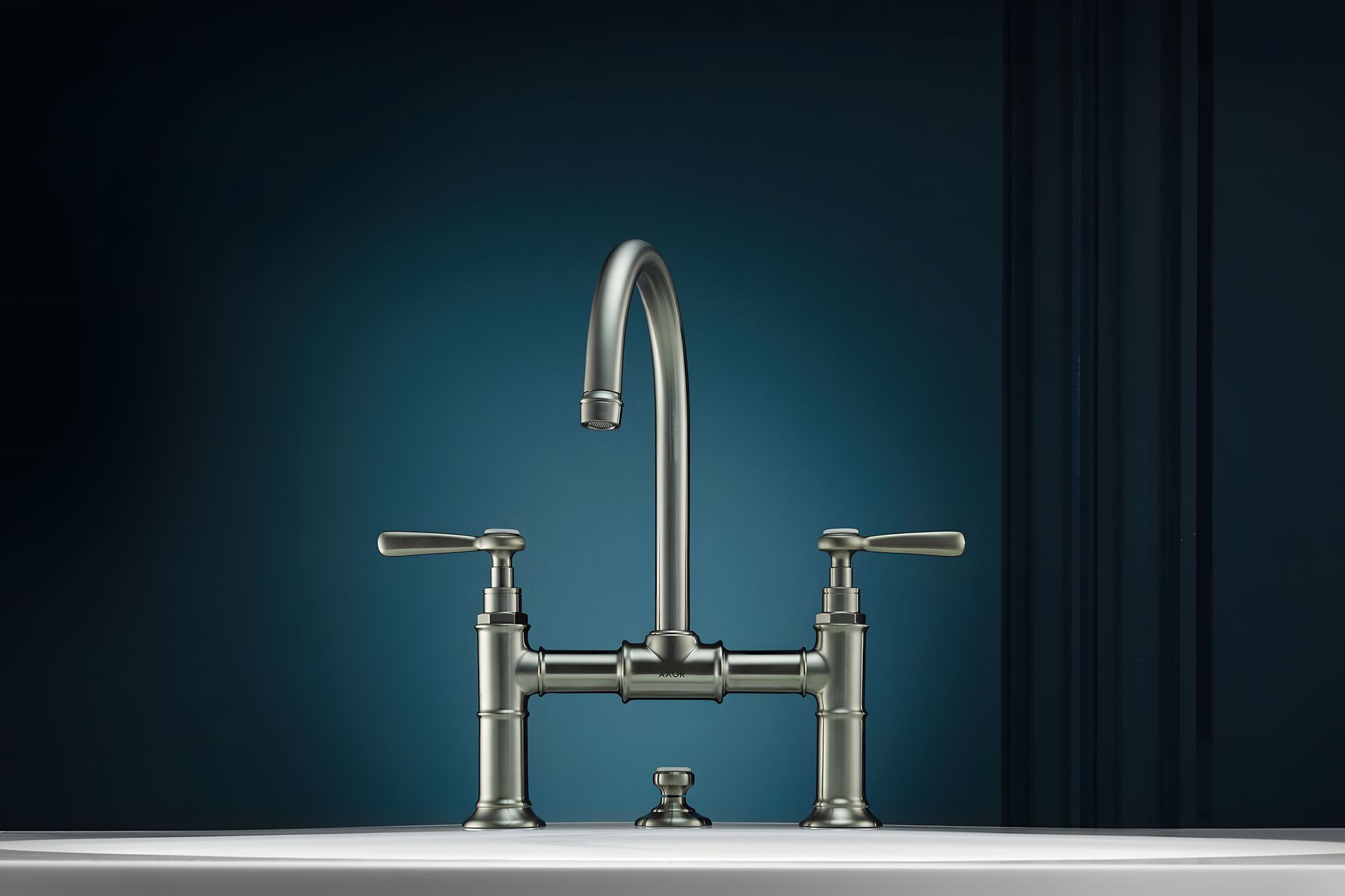 AXOR Montreux bridge basin mixer with two lever handles in front of blue wall panelling.