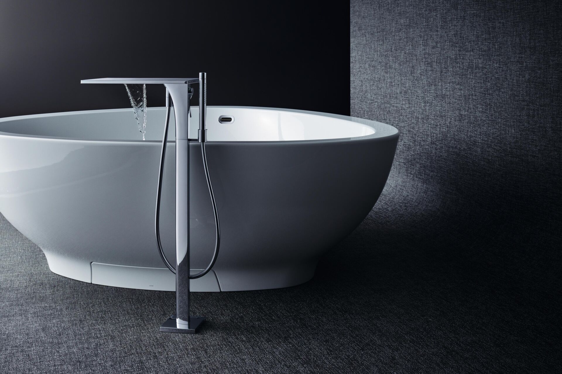 Freestanding AXOR Massaud bath mixer beside an oval white bath