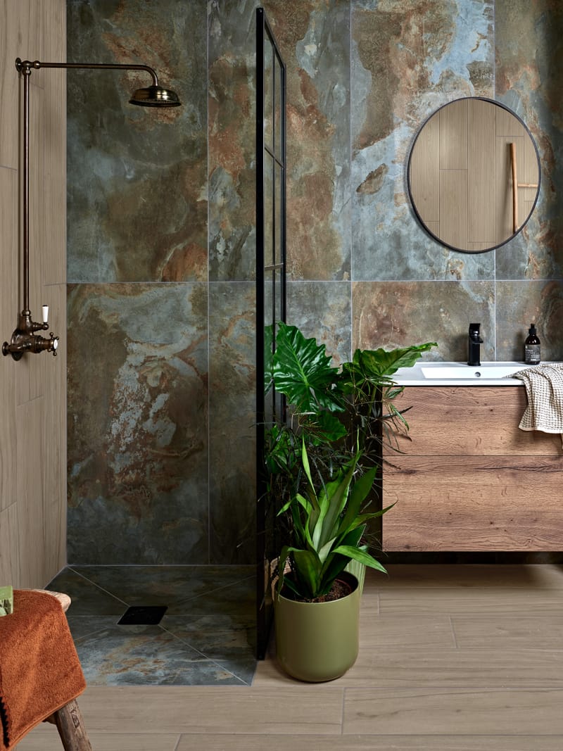 Floor-to-ceiling green and neutral tiles in a compact bathroom with walk-in shower