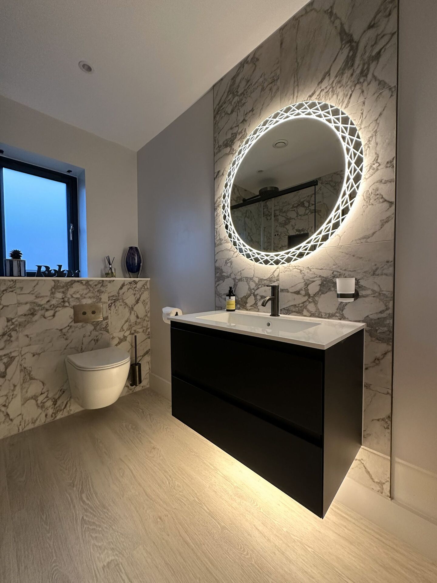 Matt black wall-hung vanity below a backlit HiB Bellus mirror, Bures CO8 ensuite shower room