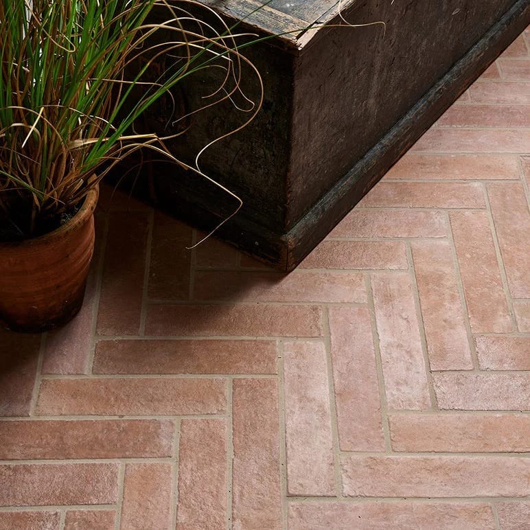Herringbone bathroom floor tiles viewed from the doorway showing directional pattern flow and visible grout lines