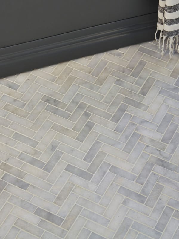 Herringbone tile installation in progress showing precise alignment and tile-setting technique