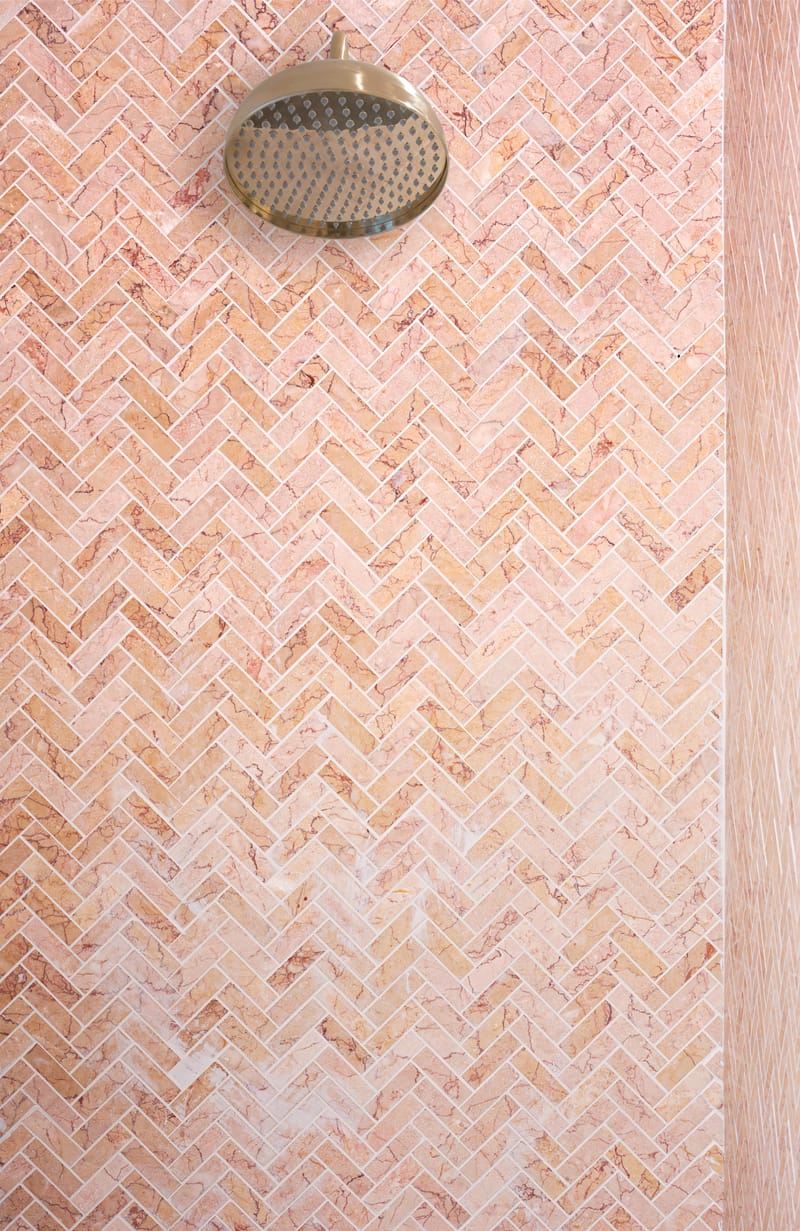 Marble mosaic herringbone tile pattern close-up showing the classic zig-zag layout in a luxury bathroom