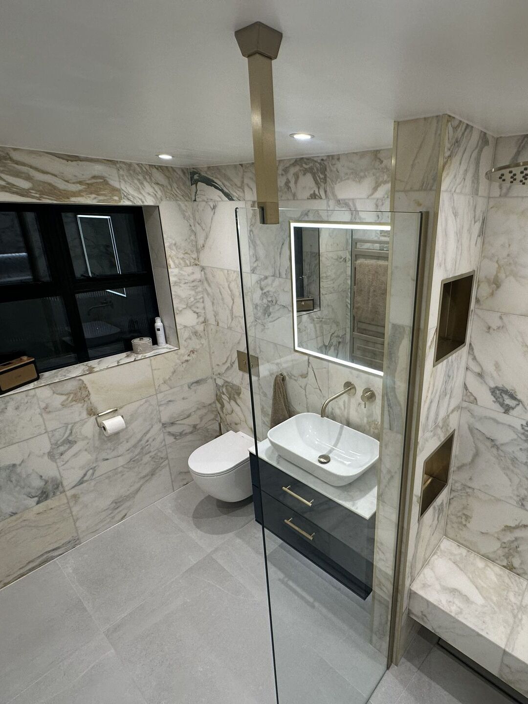 Vessel basin on a navy vanity beneath an illuminated HiB Vanquish mirror cabinet, with a wall-hung WC alongside, Chelmsford CM3 master ensuite