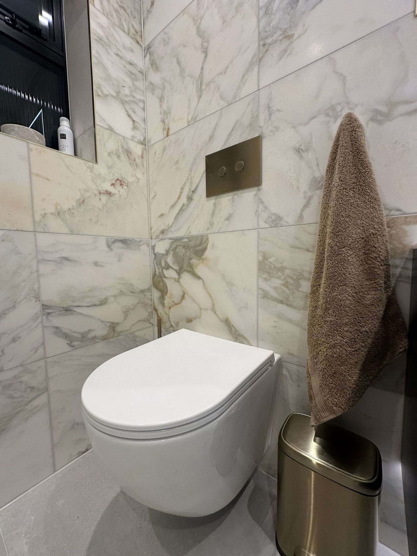 Wall-hung Geberit WC with a brushed brass flush plate against honed marble tiles, Chelmsford CM3 master ensuite
