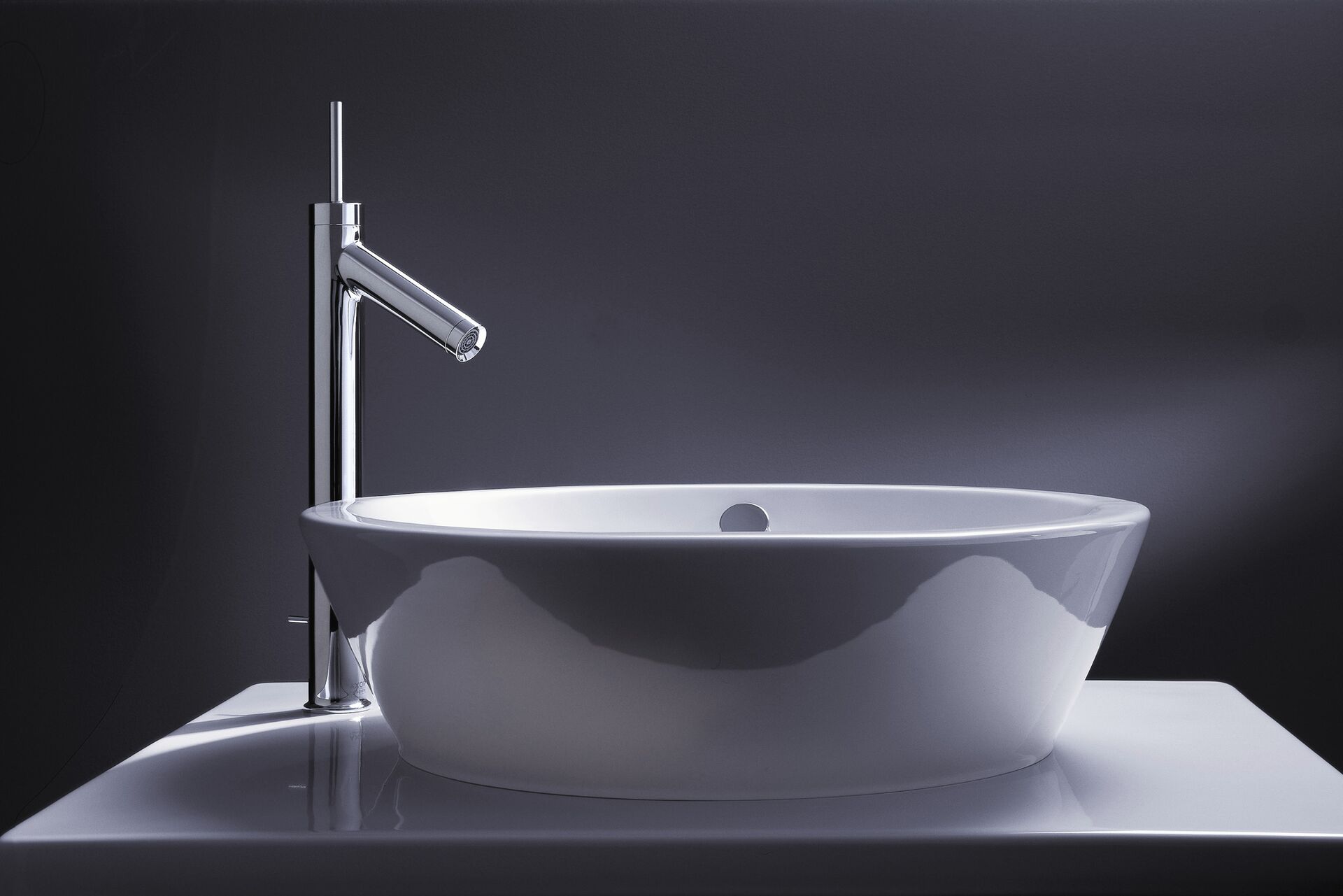 Tall AXOR Starck mixer beside a white countertop washbowl