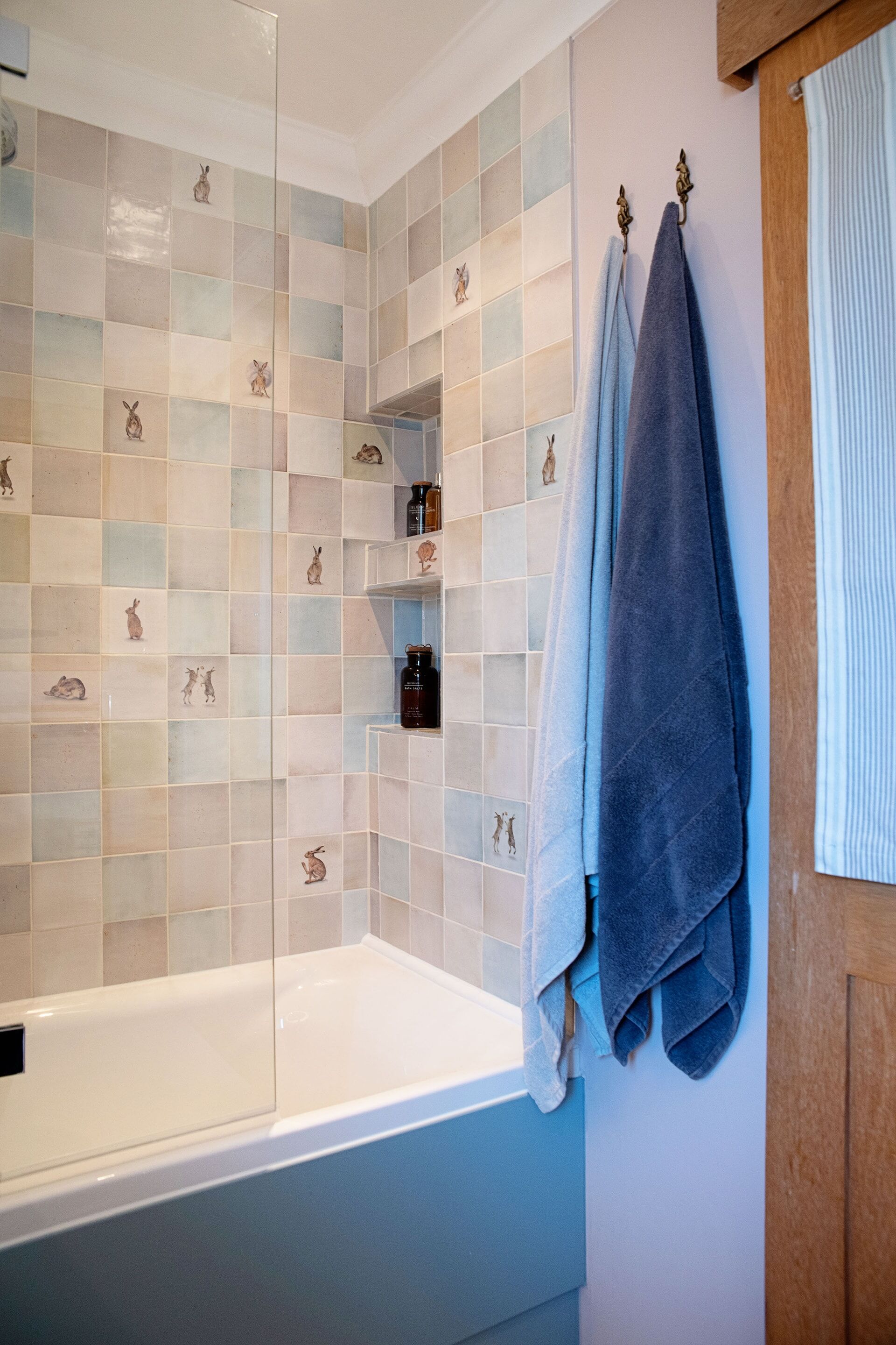 Stacked corner niches at the bath end of the Coggeshall CO6 country cottage bathroom, with Ca' Pietra Wiltshire Hares tiles scattered across the walls