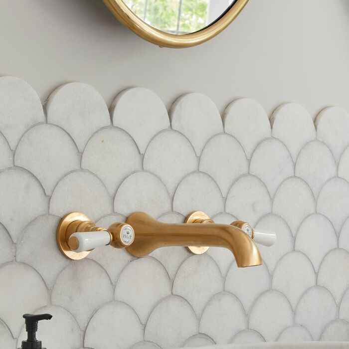 Brushed-brass tap on honed scalloped marble mosaic