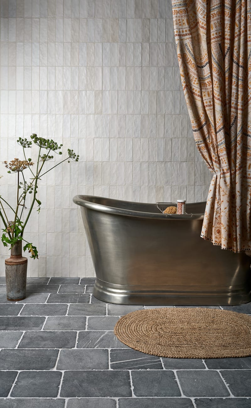 Modular stone tile layout on bathroom floor with mixed-size white matt tiles and cobblestone border