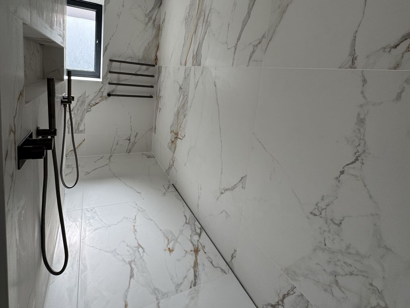 Open wet room in the Billericay CM11 master ensuite, with no glass screen and a marble-effect porcelain floor running to a linear drain along the right-hand wall