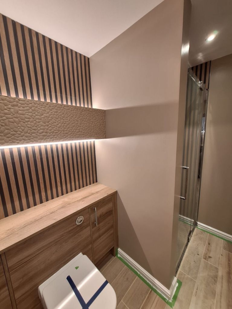 Porcelanosa Boulder lit niche above Roper Rhodes fitted furniture, with the Crosswater shower door beyond, in a Benfleet SS7 master ensuite