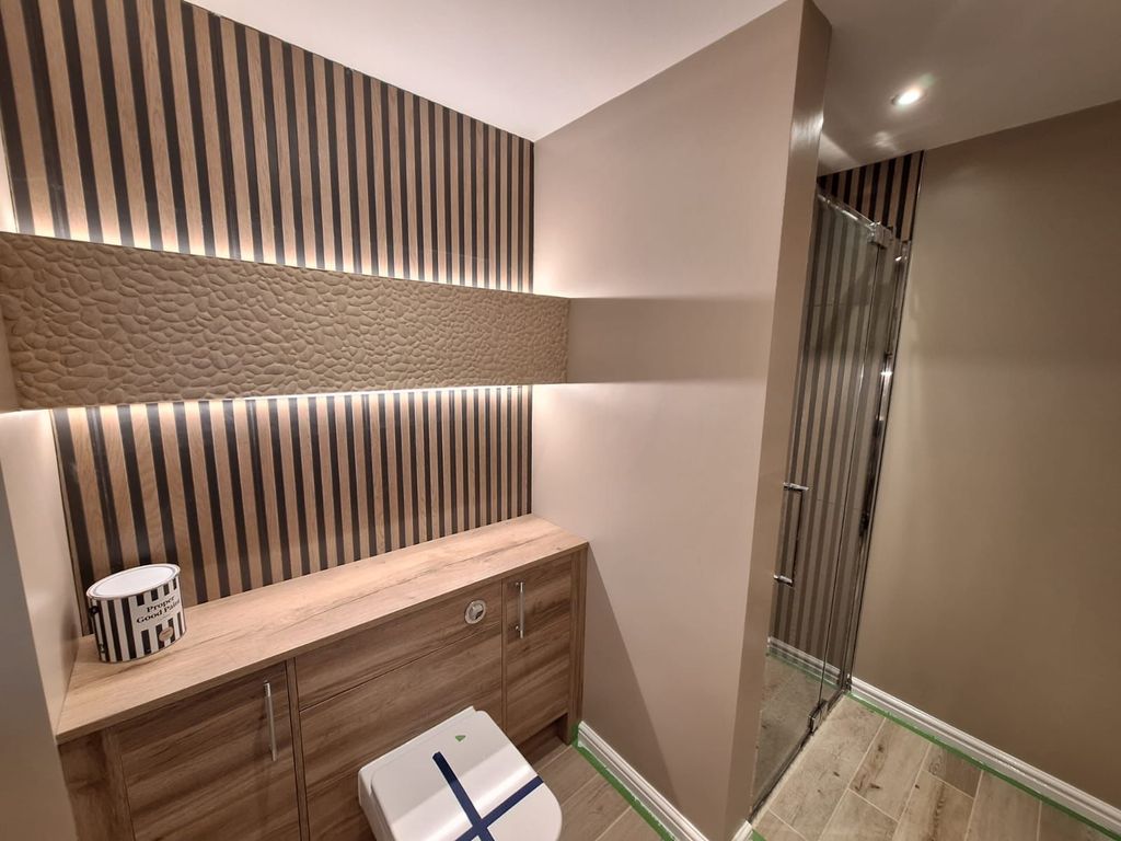 LED strip lighting behind a slatted oak wall above a Roper Rhodes furniture run, with the wetroom shower beyond, in a Benfleet SS7 ensuite
