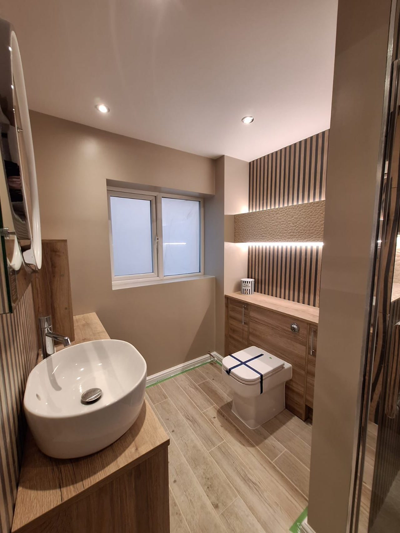 High-angle overview of Benfleet SS7 master ensuite showing basin, WC, fitted furniture, and wood-effect flooring