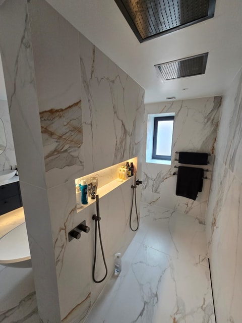Dual shower handsets with brushed black brassware and lit niche in Billericay CM11 master ensuite