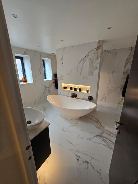 Freestanding bath close-up with lit niche above and waterfall filler in Billericay CM11 master ensuite