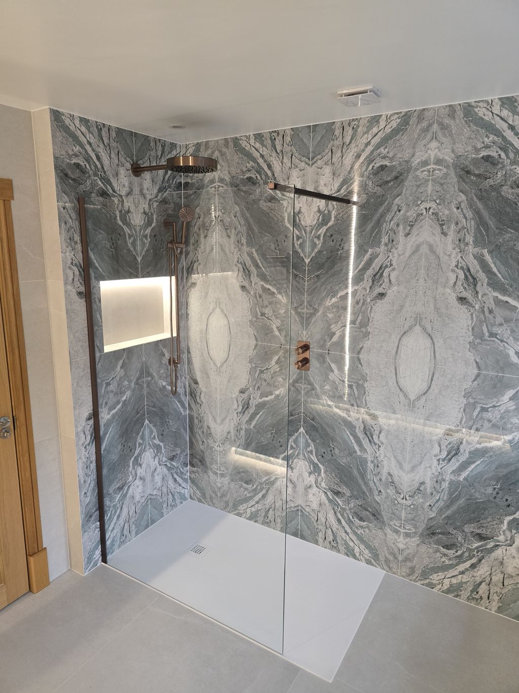 Walk-in shower with bookmatched Ocean Magnifique tiles and glass screen — Bradwell CM77