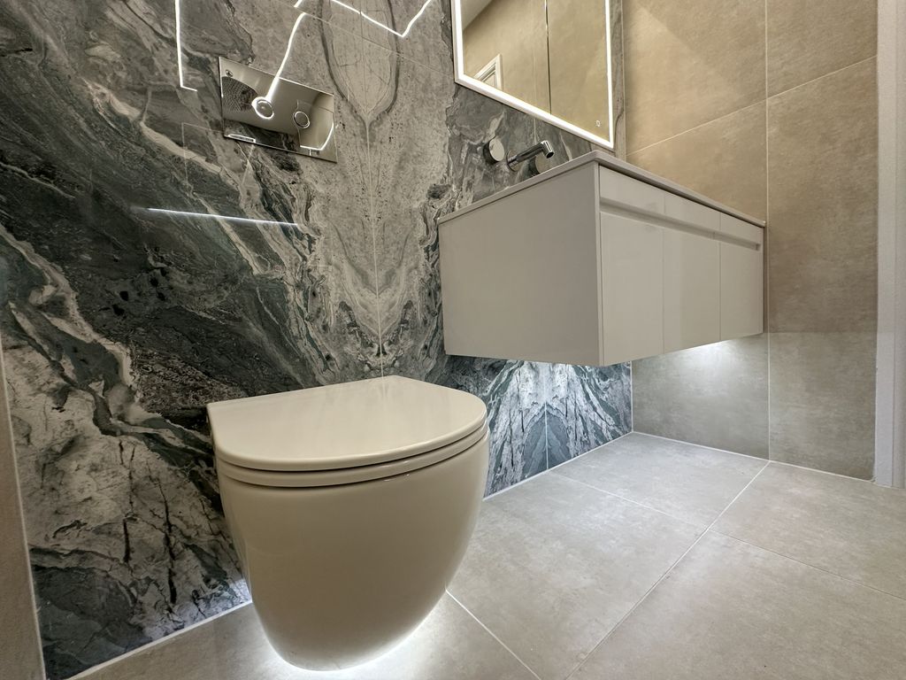 Wall-hung WC with chrome flush plate, under-vanity LED strip, and Ca' Pietra Loft Pearl wall tiles in Braintree CM7 ensuite