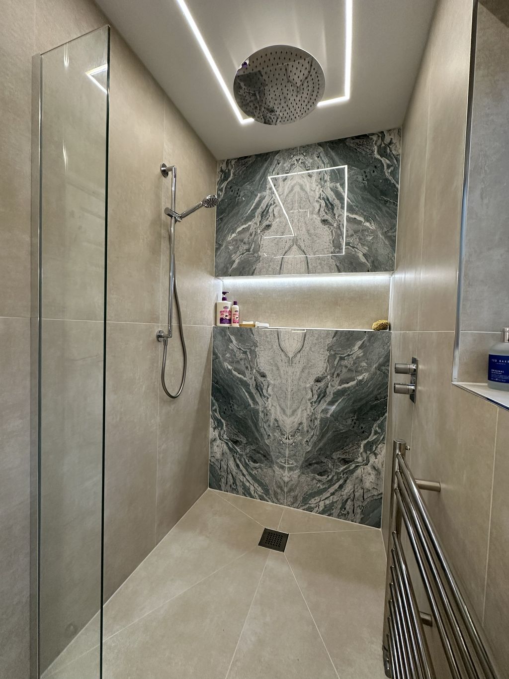 View from wetroom shower looking back through Braintree CM7 ensuite with JTP ceiling rainfall head, towel radiator, and HiB Vanquish mirror