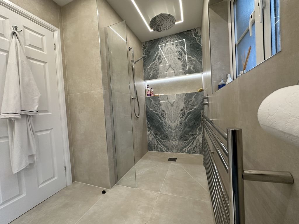 Full Braintree CM7 ensuite wetroom from doorway showing Lakes glass screen, On The Level wetroom floor, and Ocean Magnifique feature wall