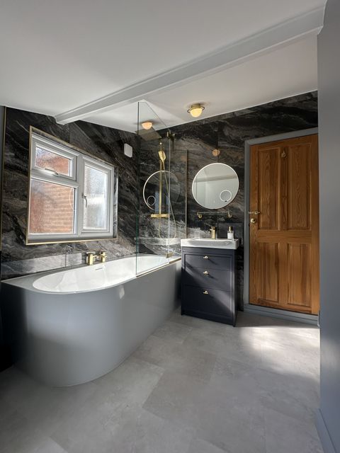 J-shape bath and Ca' Pietra Nero Magnifique bookmatched marble feature wall in a Braintree CM7 family bathroom