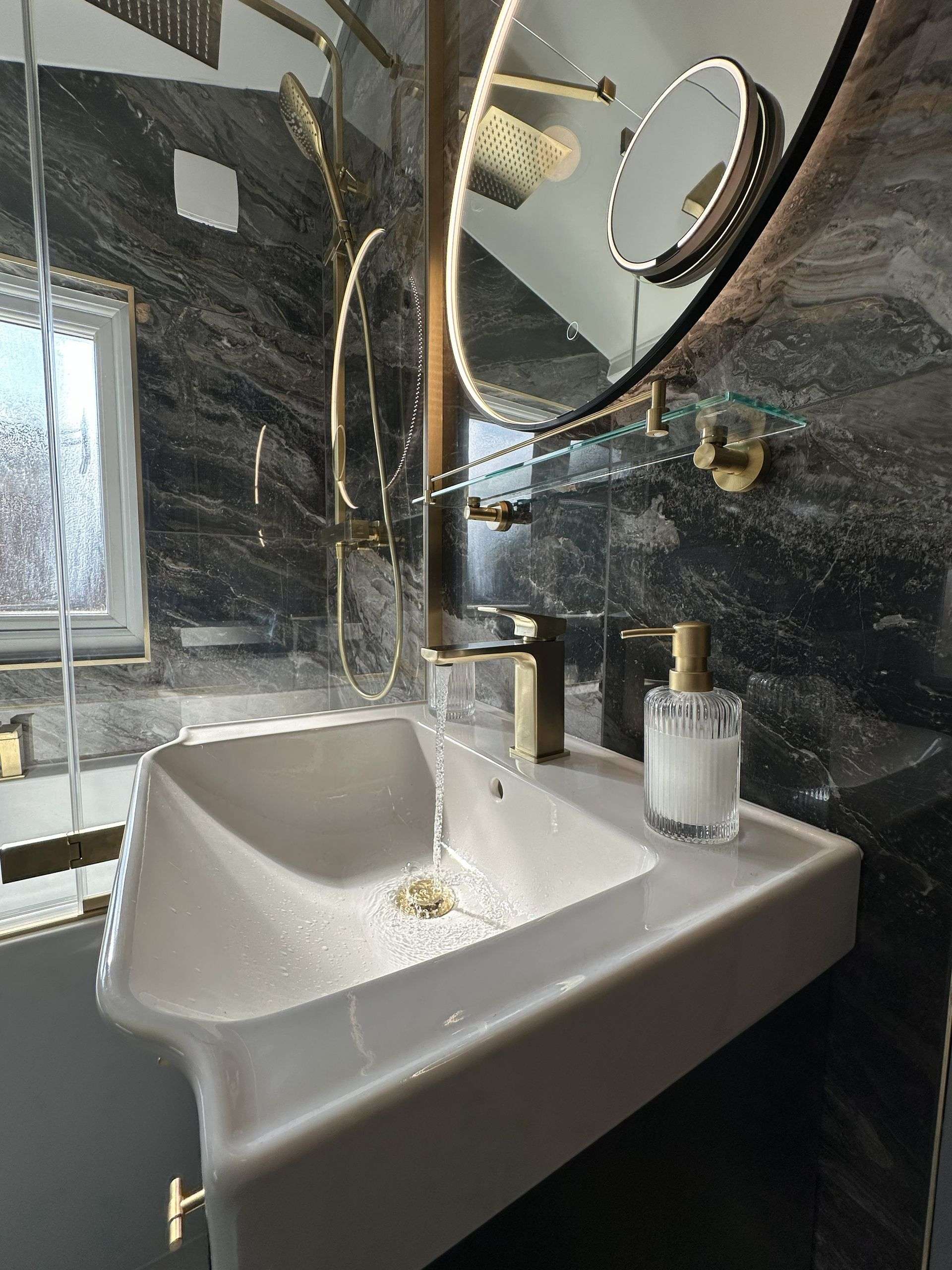 Roper Rhodes basin with brushed brass mixer tap and Ca' Pietra marble behind glass screen in Braintree CM7 family bathroom