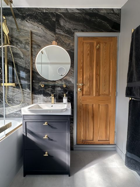 Matt navy vanity, round illuminated mirror and Ca' Pietra marble wall in a Braintree CM7 family bathroom