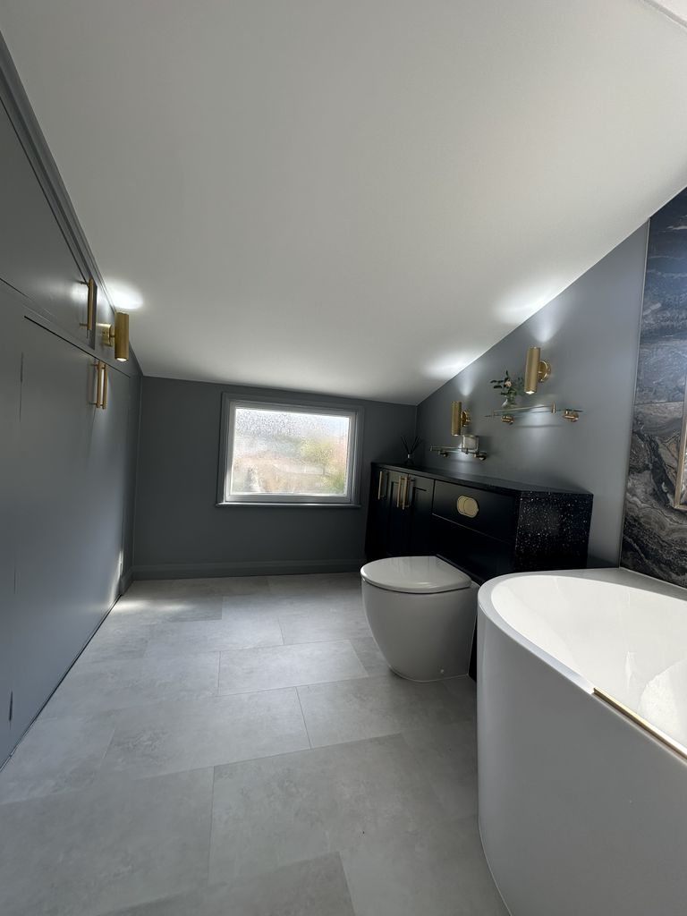 Full Braintree CM7 family bathroom view showing navy fitted storage, back-to-wall WC, Vogue brass towel rail, and tall cupboard