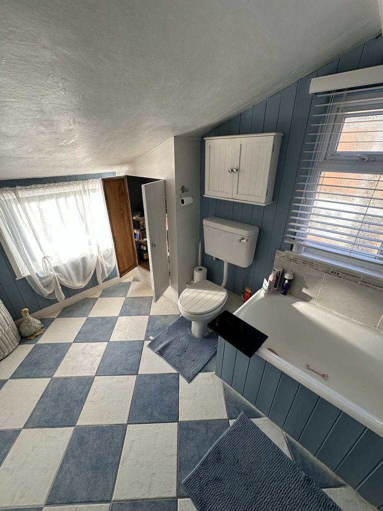 Original family bathroom Braintree CM7 before renovation showing toilet and bath area with blue panelling