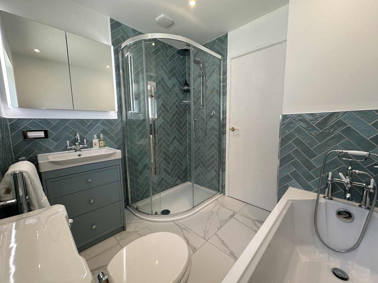 Full Brentwood CM13 family bathroom from doorway showing bath, Roper Rhodes Apex vanity, quadrant shower, and Oasis Aqua herringbone tiles