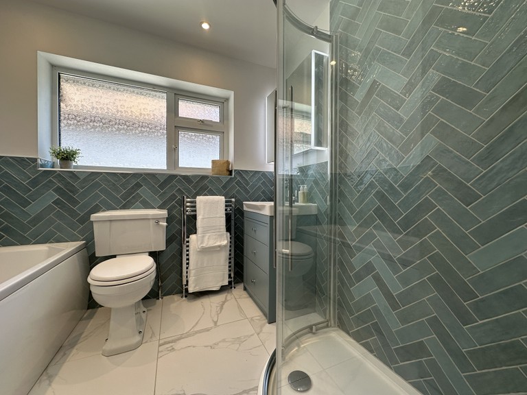 View across the Brentwood CM13 family bathroom showing bath, herringbone tiles, and quadrant shower