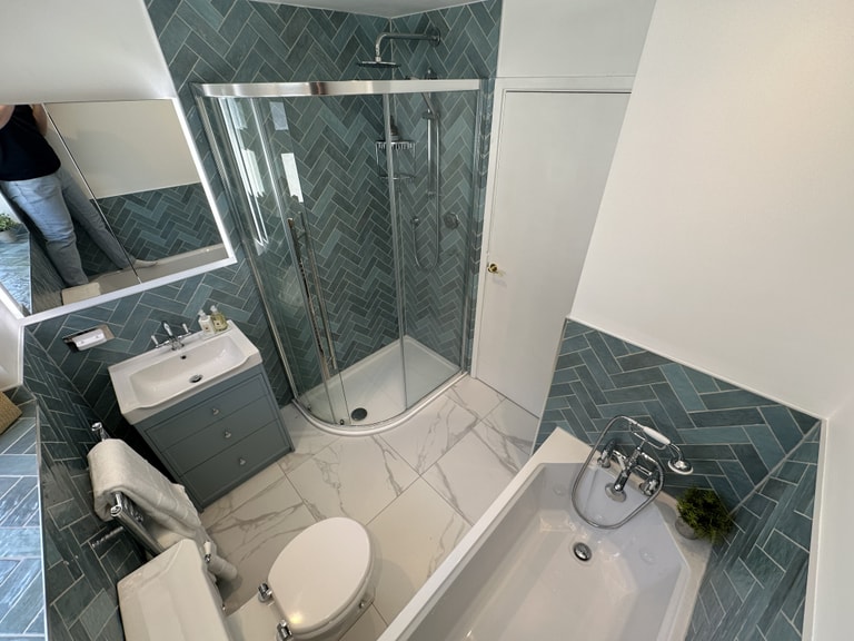 Completed double fixture family bathroom in Brentwood CM13 with herringbone tiles, quadrant shower, and Ca' Pietra Kensington floor