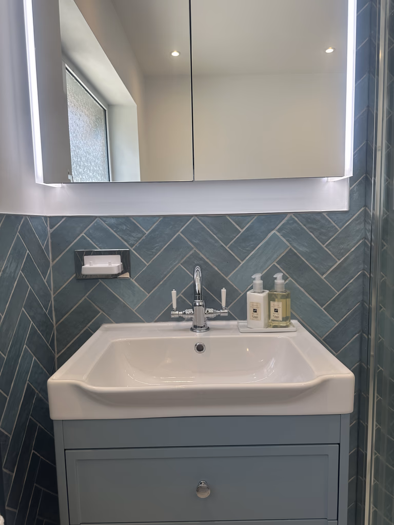 Herringbone tiled feature wall behind a glass shower screen in a Brentwood CM13 family bathroom