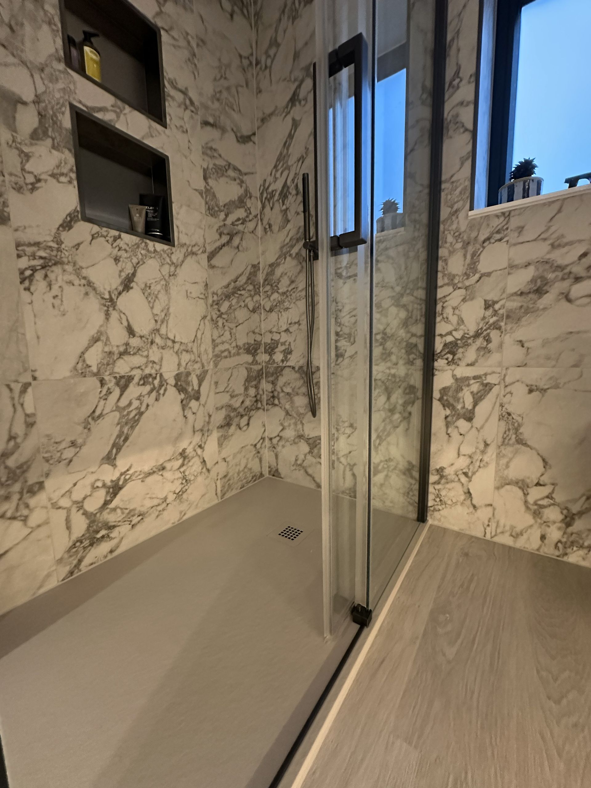 A low-profile shower tray with a shallow edge, marble-effect tiled walls, Bures CO8 ensuite