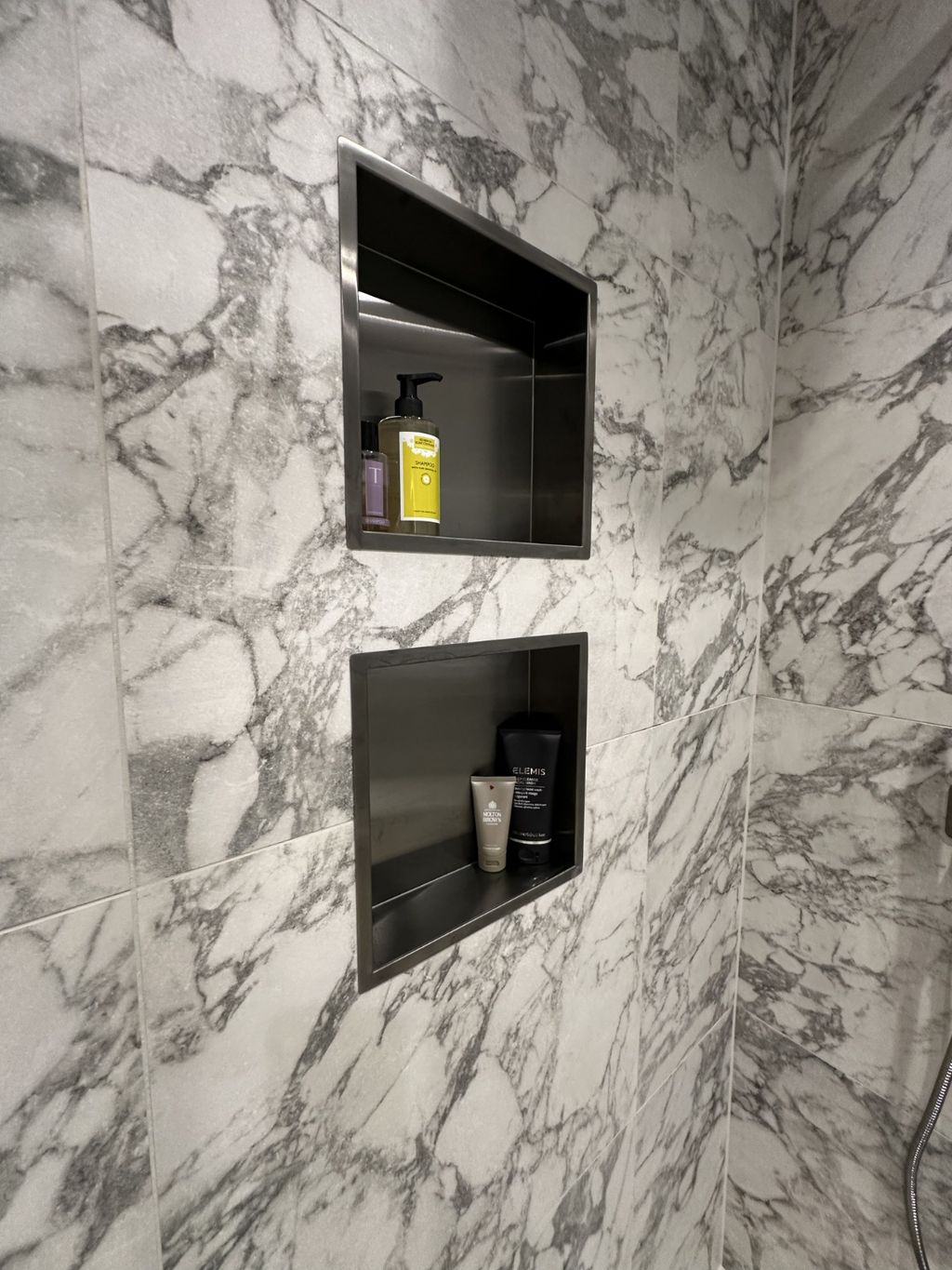 Twin stacked shower niches with brushed black frames against Ca' Pietra marble-look tiles in Bures CO8