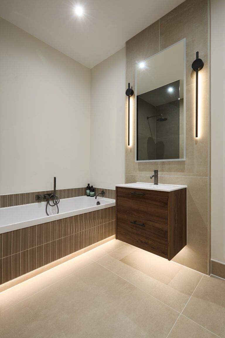Walnut vanity mirror and bath with fluted tile panel Chelmsford CM2 Essex family bathroom Bowman Bathrooms