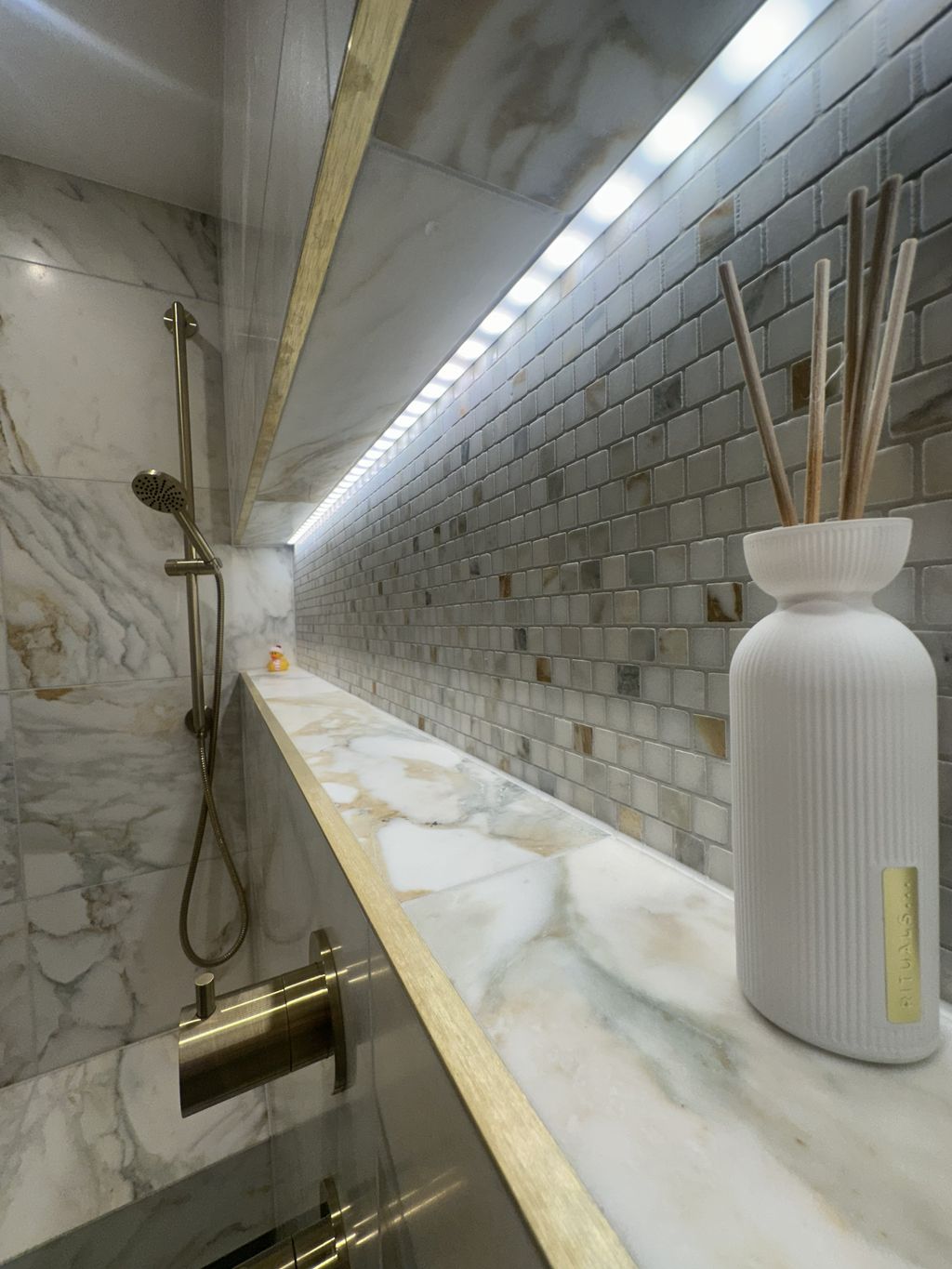 Infinity niche close-up with marble mosaic tiles LED strip lighting and brushed brass trim Chelmsford CM3