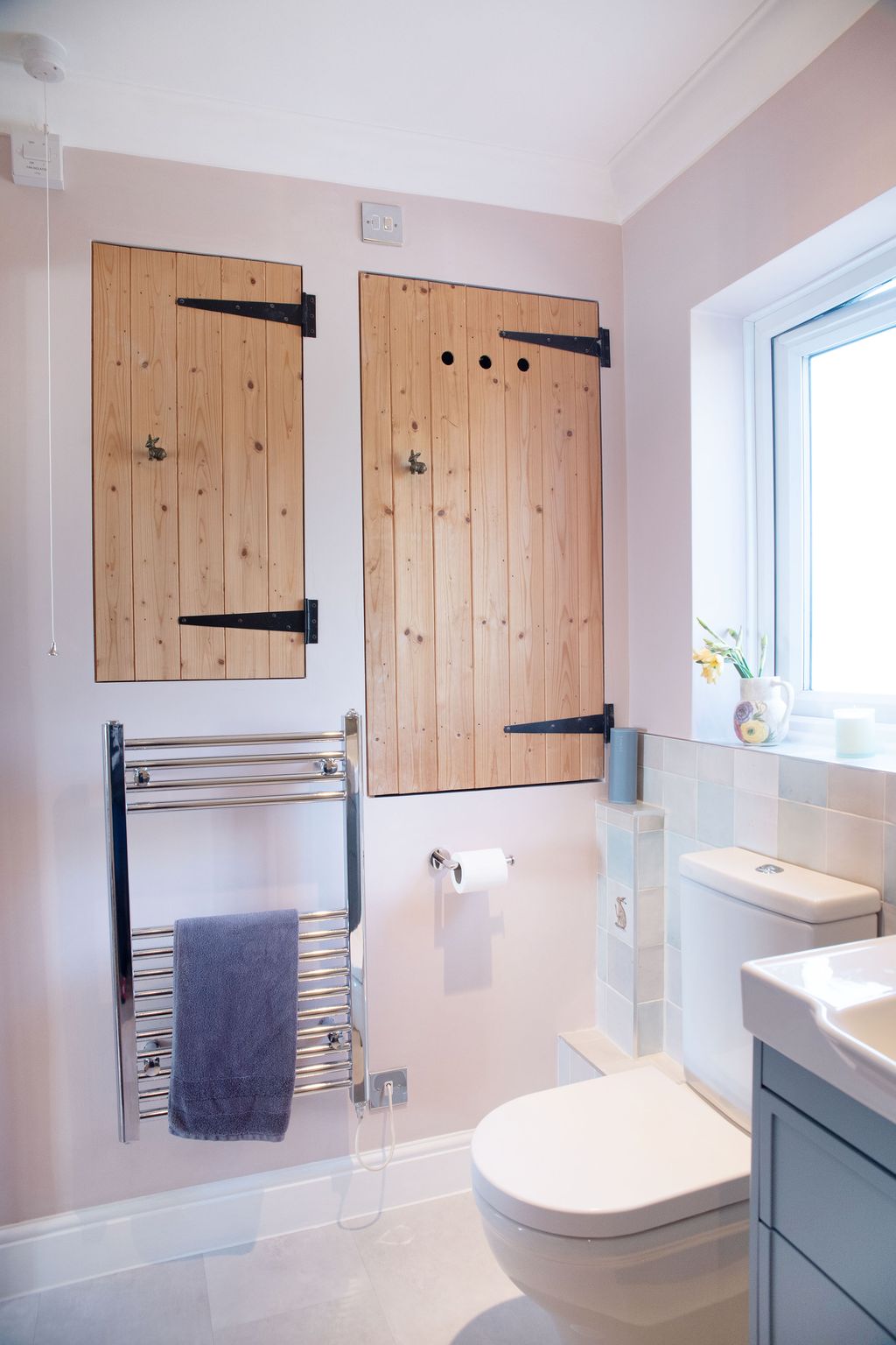 Langford WC with rustic wooden airing cupboard doors chrome towel rail and window in Coggeshall CO6 cottage bathroom