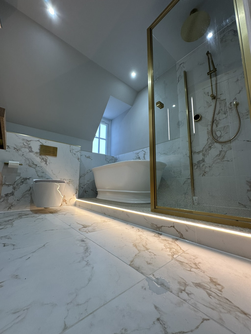 Full room view LED strip glow marble effect floor brass shower enclosure and freestanding bath Colchester CO1