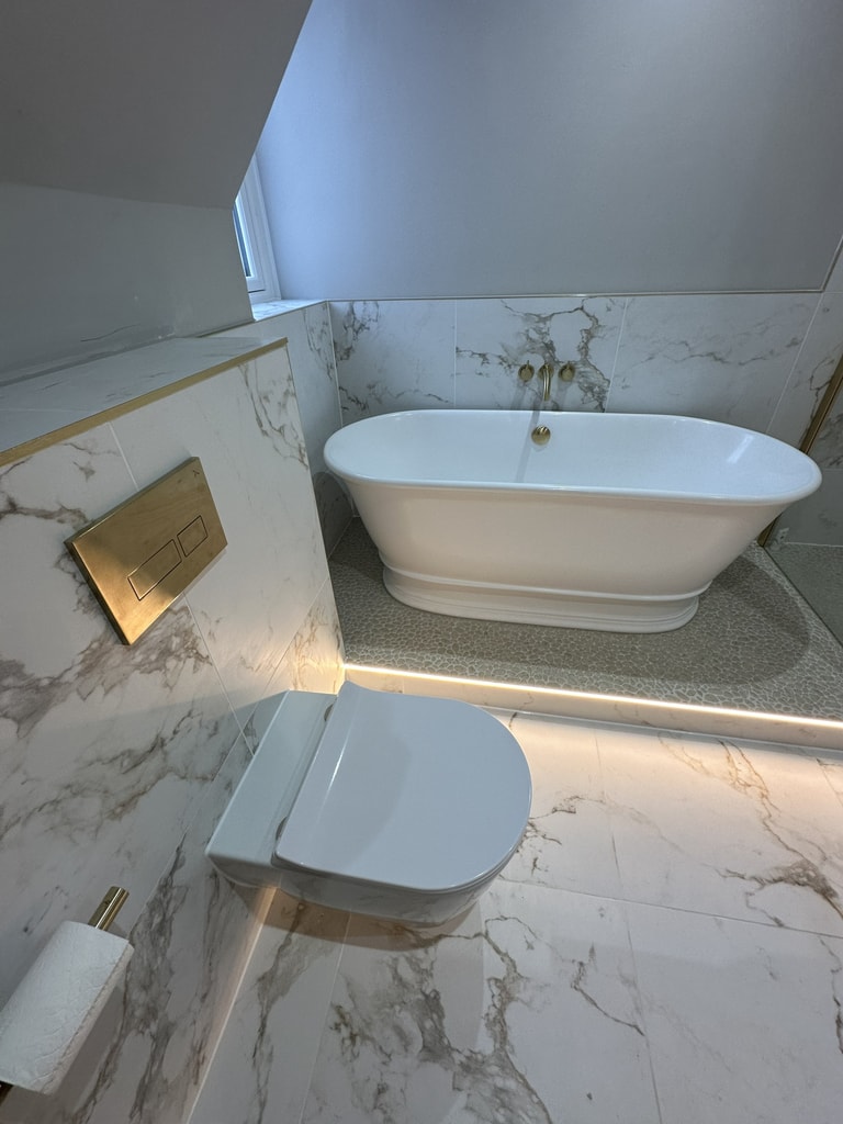 Brushed brass Crosswater flush plate and wall-hung WC beside the freestanding bath in a Colchester CO1 bathroom