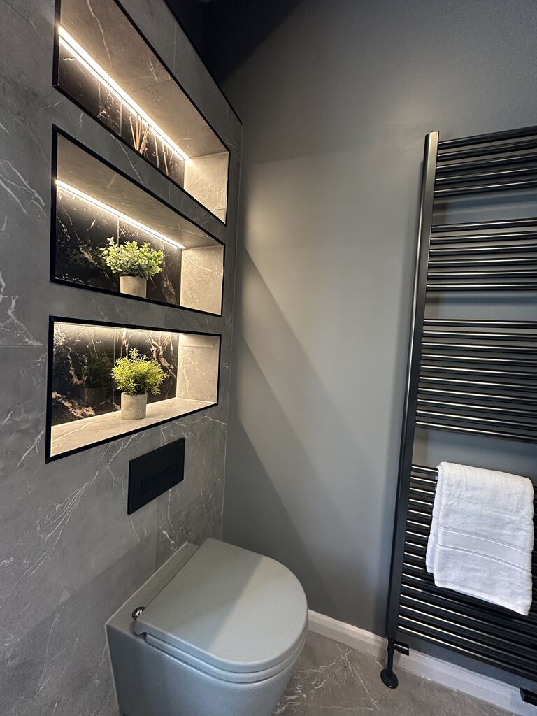 Black ladder towel radiator beside backlit niches and wall-hung WC Gosfield CO9 Essex